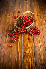 ripe red dogrose in a basket on a wooden