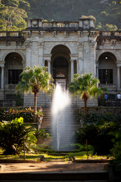 Sunlight streaming in in the gardens of Parque Lage school with the water of the fountain in front catching sunlight