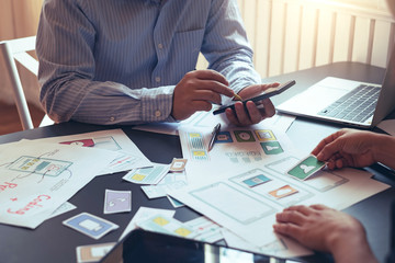 Designers planning to work together Draw application program in mobile phone and website development.