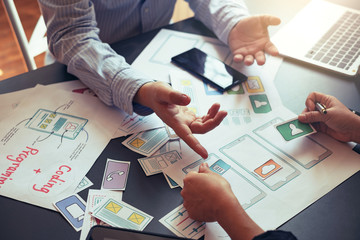 Designers planning to work together Draw application program in mobile phone and website development.
