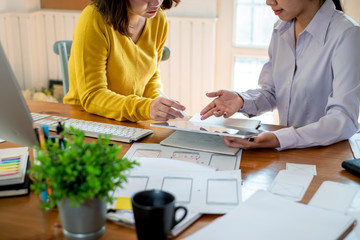 Two female designers drawing a website outline and website ux app development on mobile phone.