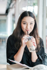 Charming Asian woman sitting drinking pearl milk tea happily.