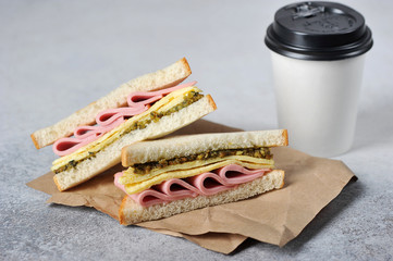 Sandwich with ham, omelet and cheese  and paper cup with coffee. The concept of fast food and...