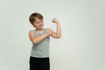 Photo is a waist-high portrait of a fun cheerful cute happy school-age athlete boy in a T-shirt. Rejoices, smiles on a white background. Shows hands.