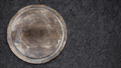 Wooden plate or cutting board with flour on a dark, black background with copy space