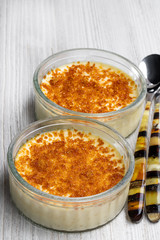 Closeup of creme brulee in glass jars on white wooden table