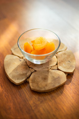 Dried apricots in a glass bowl on a round wooden board