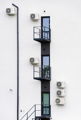 Abstract architecture picture with doors, balconies, some air conditioning and cctv security camera on gray industrial wall.