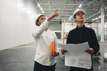 Two building engineers with blueprint working on construction site. Industrial enginer and worker...