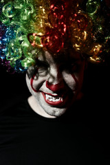 Portrait of an evil creepy clown. Man in clown makeup for Halloween holiday.
