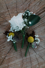 white rose and billy balls craspedia flower boutonnières on wooden background