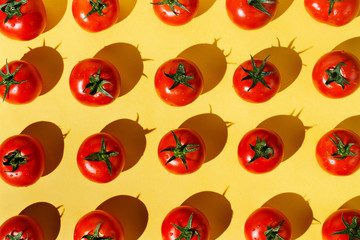 Flatlay of fresh red ripe tomatoes knolled on yellow