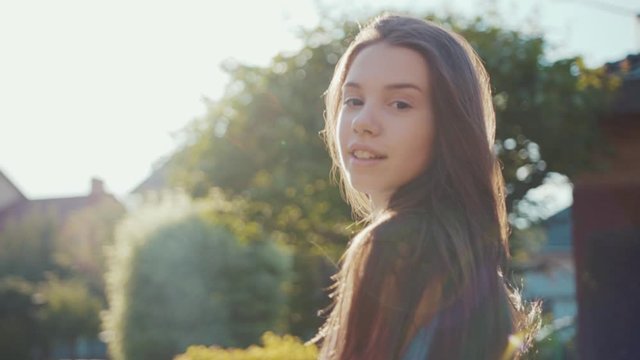 Portrait beautiful girl walk poses look at camera smile in the sun at sunset relaxing outdoors park summer teenage cute face female hair outside attractive field freedom slow motion