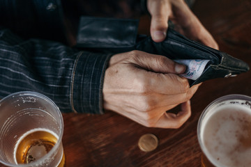 Hands get money from the wallet. Near glass of beer
