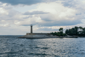 Fototapeta premium Lighthouse on edge of concrete breakwater on wide river