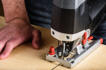 Man with electric jig saw cutting wood