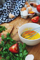 cooking process, ingredients, hearty and healthy breakfast, scramble eggs with tomatoes and herbs on toast with black tea on a wooden background