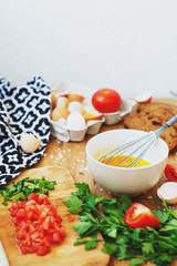 cooking process, ingredients, hearty and healthy breakfast, scramble eggs with tomatoes and herbs on toast with black tea on a wooden background