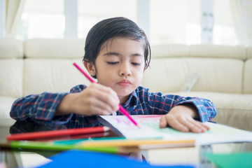 Cute little boy drawing on a paper at home