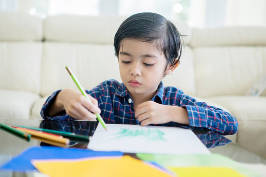 Cute little boy drawing with color pencils at home