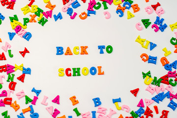 Text Back to school in colored wooden letters on white background.