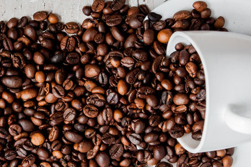 Black coffee in white cup and coffee beans on light wooden background. Top view, space for text