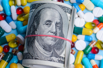 Pack of dollars lay on medicine pills, capsules with hard glance to the camera. Concept of...