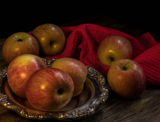 Apples and silver plate on the dark wooden table