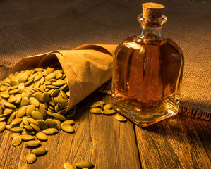 pumpkin seeds in the dark paper bag and oil on the wooden table