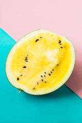 half of ripe yellow watermelon on pink-blue background
