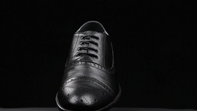 Rotation and approximation of black classic men's shoes on a black background. Copy space.