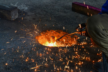 A gas cutter in production, a welder removes unnecessary metal residues with a gas cutter, sparks...