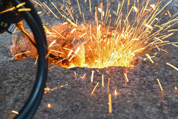 A gas cutter in production, a welder removes unnecessary metal residues with a gas cutter, sparks...