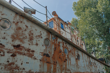 Board with portholes of an old rusty abandoned ship. Old rusty abandoned ship on land