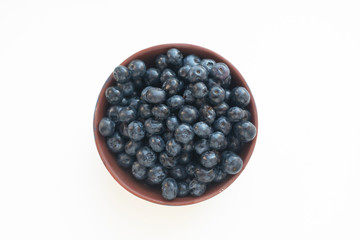 Blueberries in a clay bowl isolated on white background. High resolution, organic food, top view. Ingredients