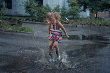Fototapeta premium Baby girl jumping in the puddles.