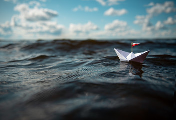 Papierschiff in hohen Wellen auf See