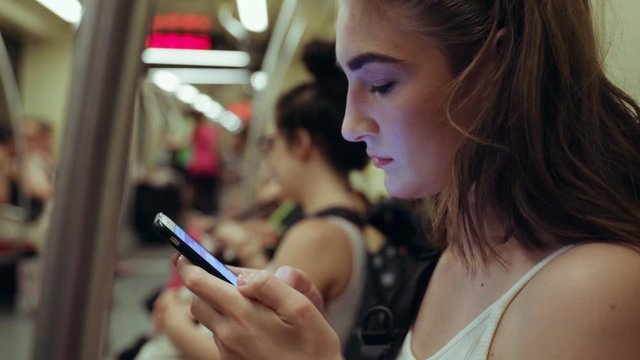 Young pretty woman use writes a message in smartphone rides the underground metro phone public car subway technology train transport travel cellphone close up slow motion