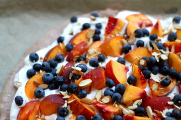 Chocolate Pavlova cake with whipped cream, peaches, blueberries and almonds. Selective focus.