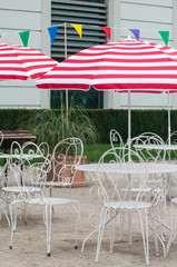 closeup of metallic chairs and white and red umbrella in restaurant terrace in outdoor
