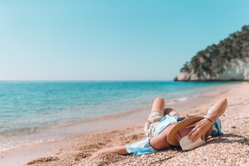 Woman laying on the beach enjoying summer holidays looking at the sea