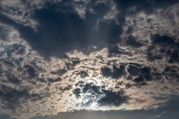 Looking up at white and dark clouds obscuring the sun