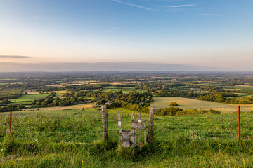 Looking out over the Sussex countryside from Ditchling Beacon, with a stile in a fence in the...