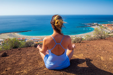 Woman doing Yoga Meditation on top of the mountain in Tenerife Canary Islands SPain