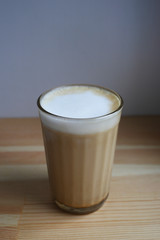 Tasty aromatic morning coffee in a glass faceted glass on a wooden table on a white background, daylight