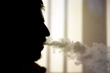 Close-up of man silhouette throwing smoke with a vaporizer