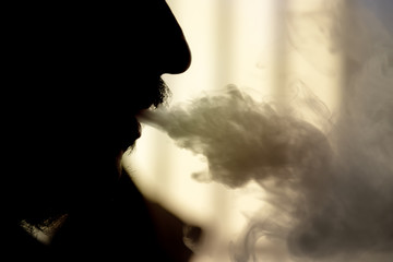 Close-up of man silhouette throwing smoke with a vaporizer