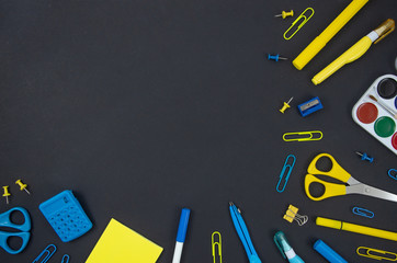Top view back to school concept, frame mockup with copy space, blue and yellow felt-tip pens, paper clips, scissors, ruler. Stationery on a blackboard background