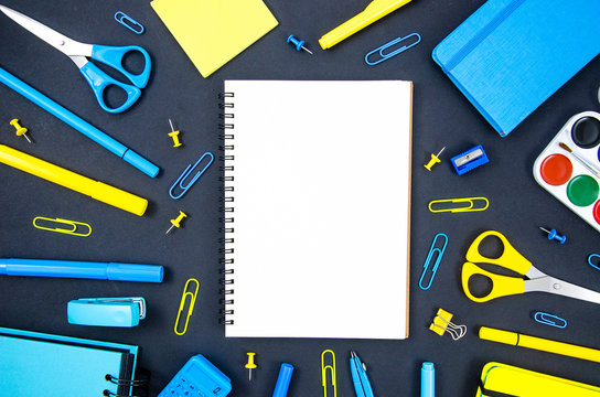 Top view back to school concept, workspace flatlay mockup with blank notepad and copy space, felt-tip pens, paper clips, scissors, ruler. Stationery on a blackboard