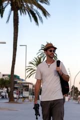 Modelo paseando delante de la playa con sombrero y gafas